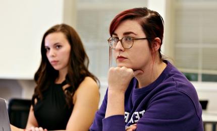 Two TCU graduate students laugh in a spirited exchange in their Communication Studies class